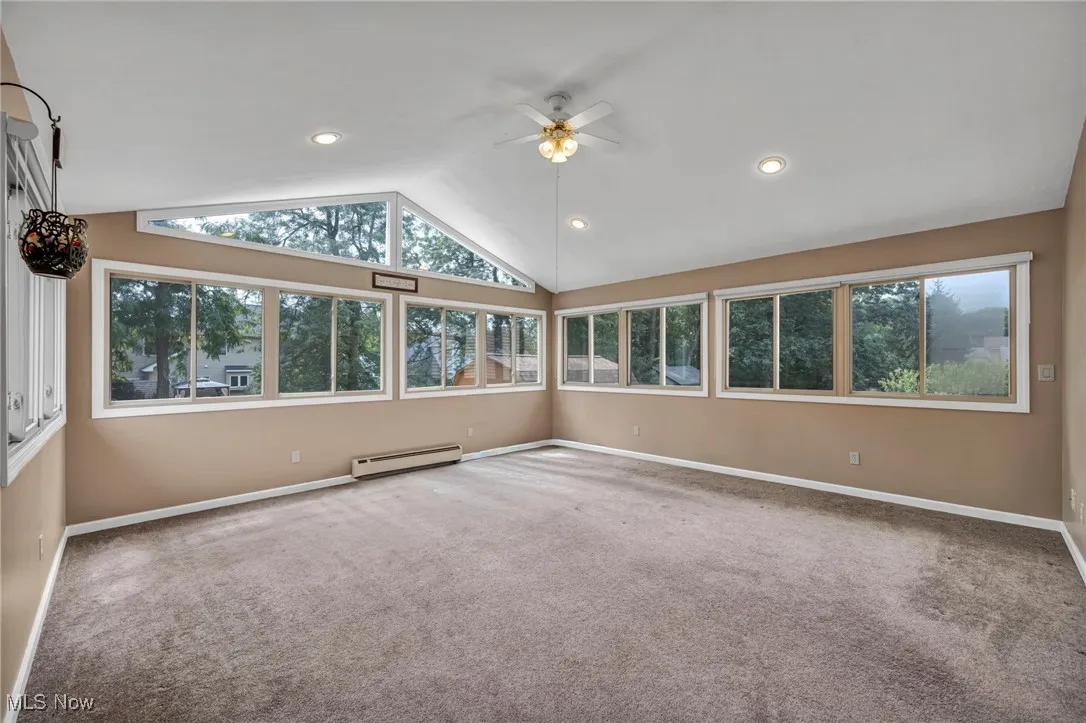 Carpeted spare room featuring a baseboard radiator, ceiling fan, recessed lighting, and high vaulted ceiling