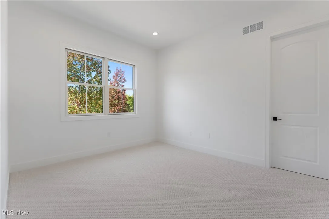 Carpeted empty room with recessed lighting and baseboards