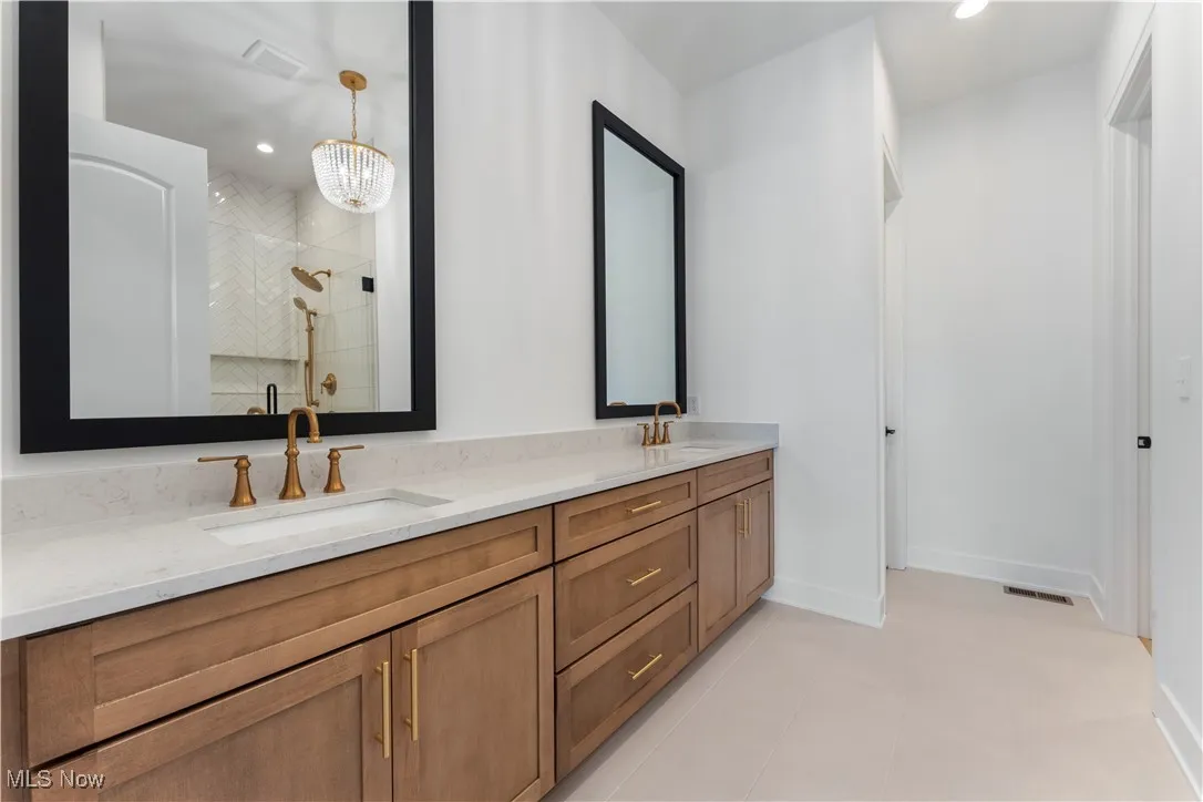 Full bathroom featuring double vanity, light tile patterned flooring, recessed lighting, and tiled shower