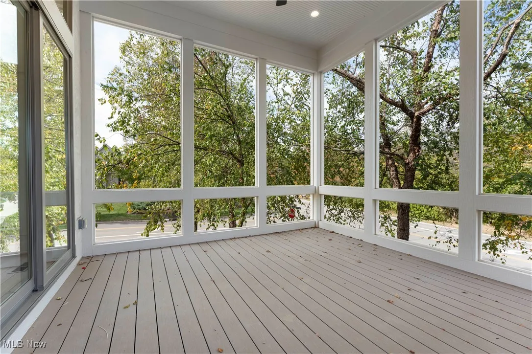 Unfurnished sunroom featuring a deck and view of wooded area