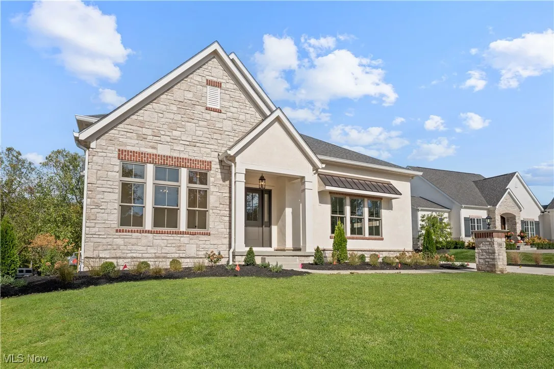View of front of home with stone siding, a front yard, and stucco siding