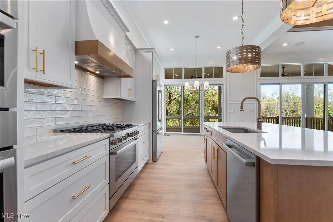 Kitchen featuring stainless steel appliances, light stone countertops, premium range hood, recessed lighting, and decorative backsplash