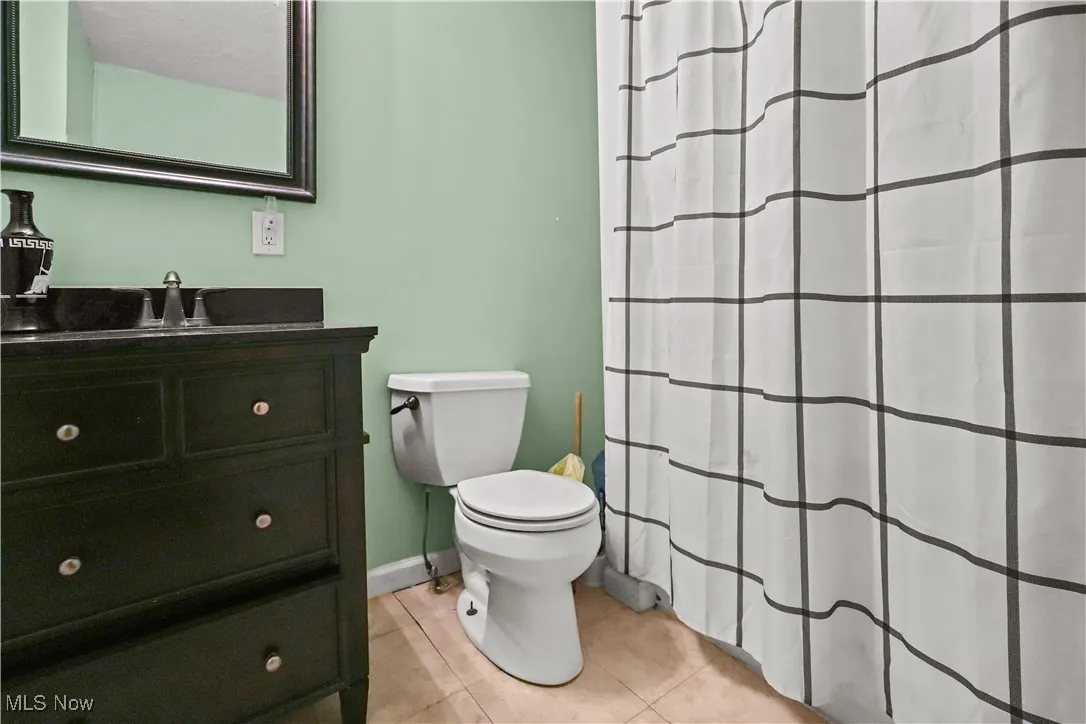 Bathroom featuring a shower with curtain, vanity, and light tile patterned floors