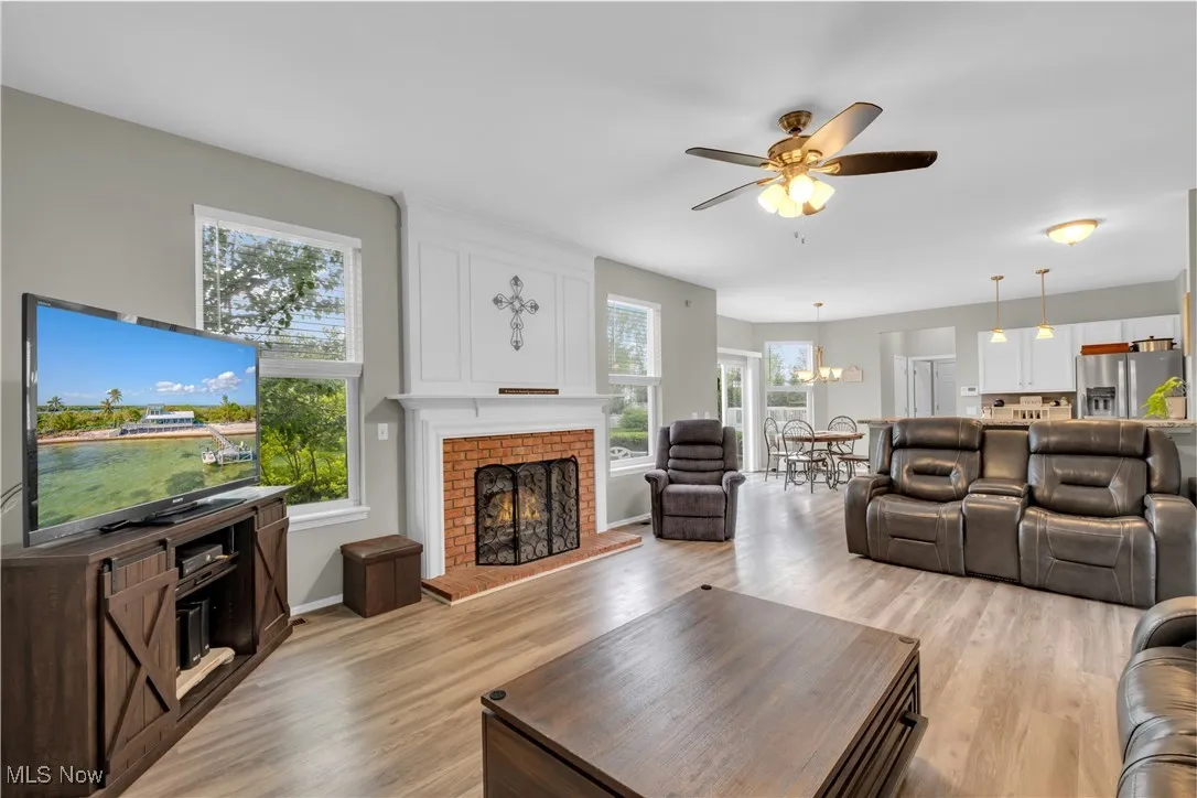 Living area with light wood finished floors, plenty of natural light, and a ceiling fan
