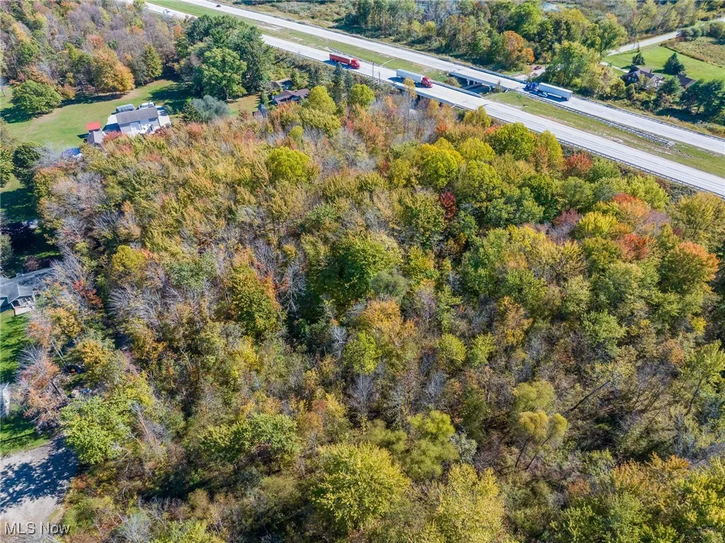 Aerial view of property and surrounding area featuring a tree filled landscape