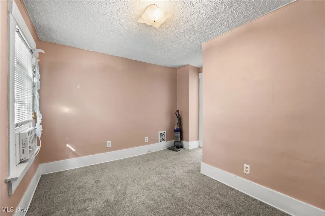 Carpeted spare room with a textured ceiling and cooling unit