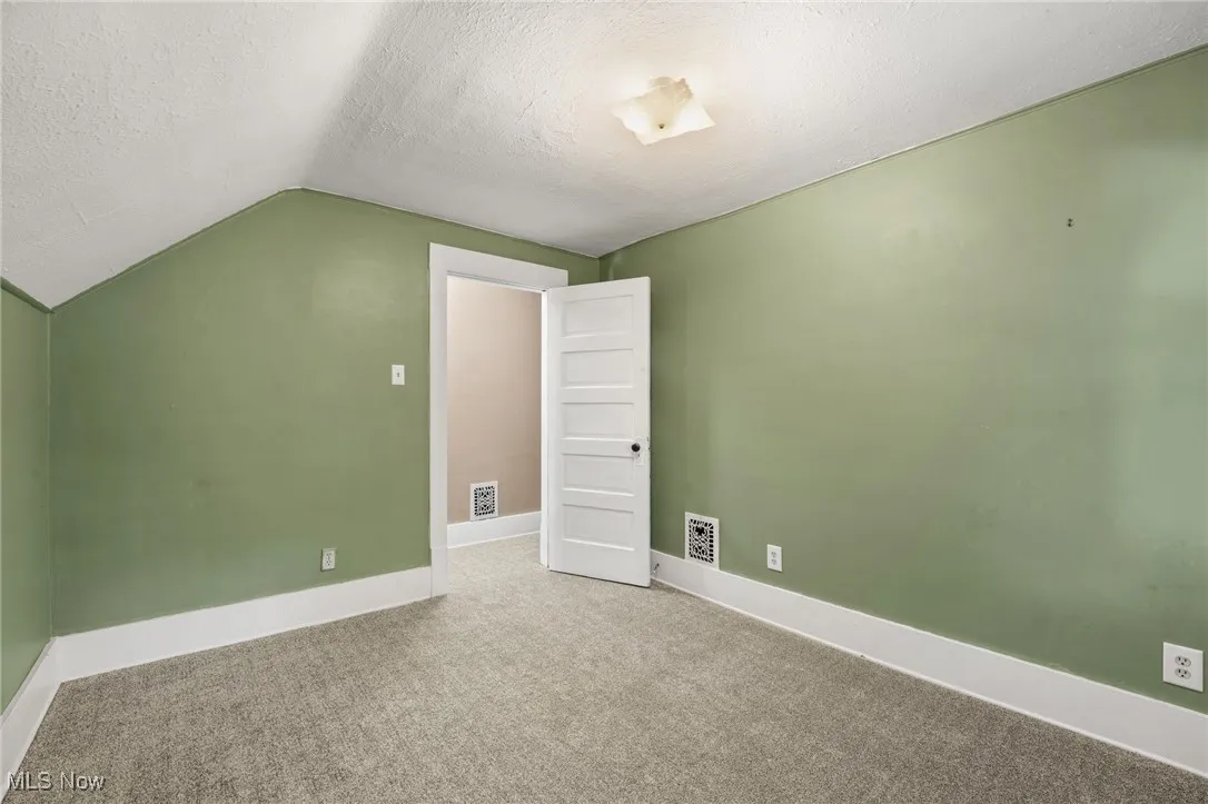 Additional living space with a textured ceiling, carpet, and lofted ceiling