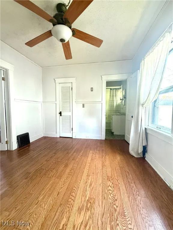Unfurnished bedroom featuring wood finished floors, ceiling fan, and a textured ceiling