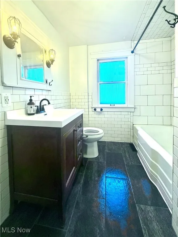 Upstairs bathroom with tile walls, vanity, and shower / bath combination