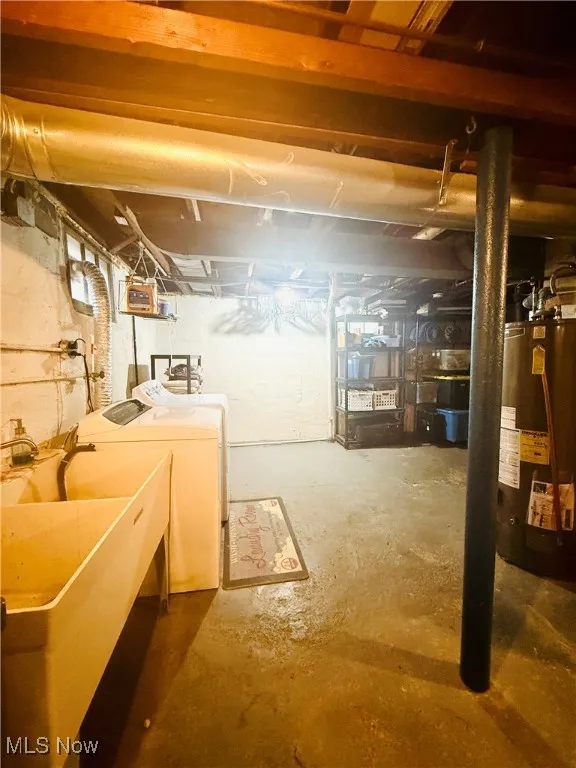 Unfinished below grade area with gas water heater and washer and clothes dryer