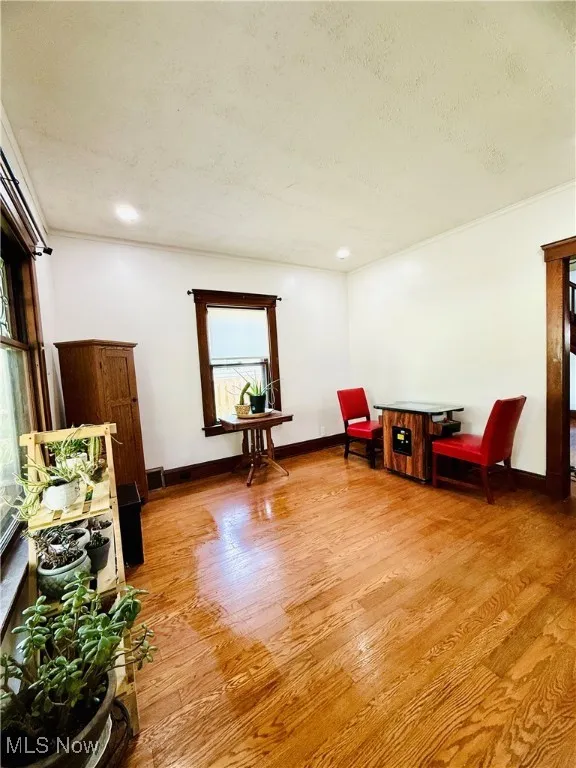 Living area featuring light wood-type flooring, crown molding, and a textured ceiling