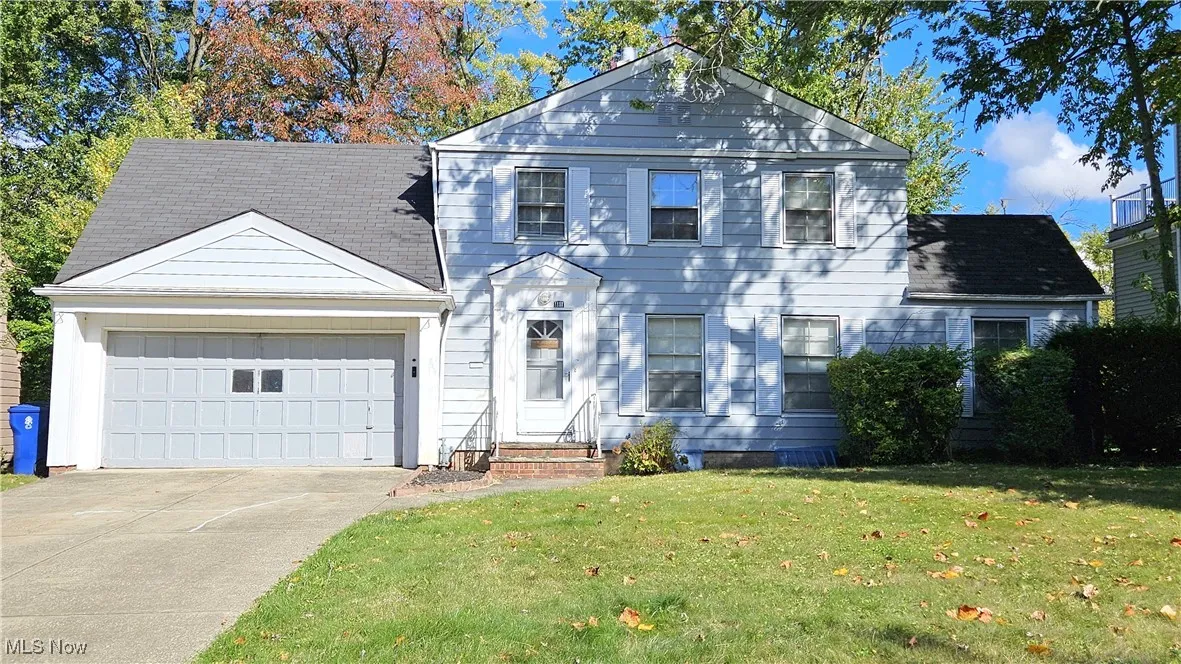 View of front of home with a front yard, an attached garage, concrete driveway, and a shingled roof