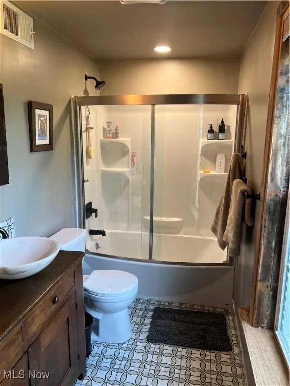 Bathroom featuring shower / bath combination with glass door, vanity, and light tile patterned flooring