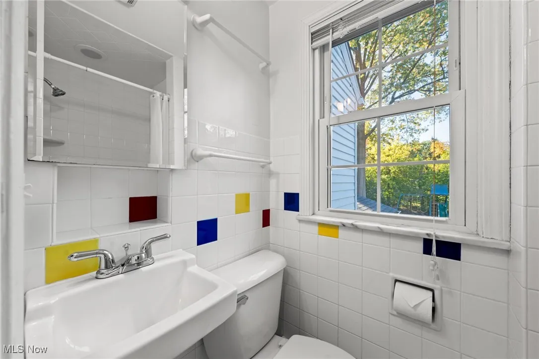 Bathroom featuring plenty of natural light, tile walls, and a shower with shower curtain
