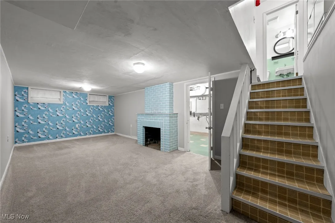 Below grade area with a brick fireplace, stairs, carpet, and a textured ceiling