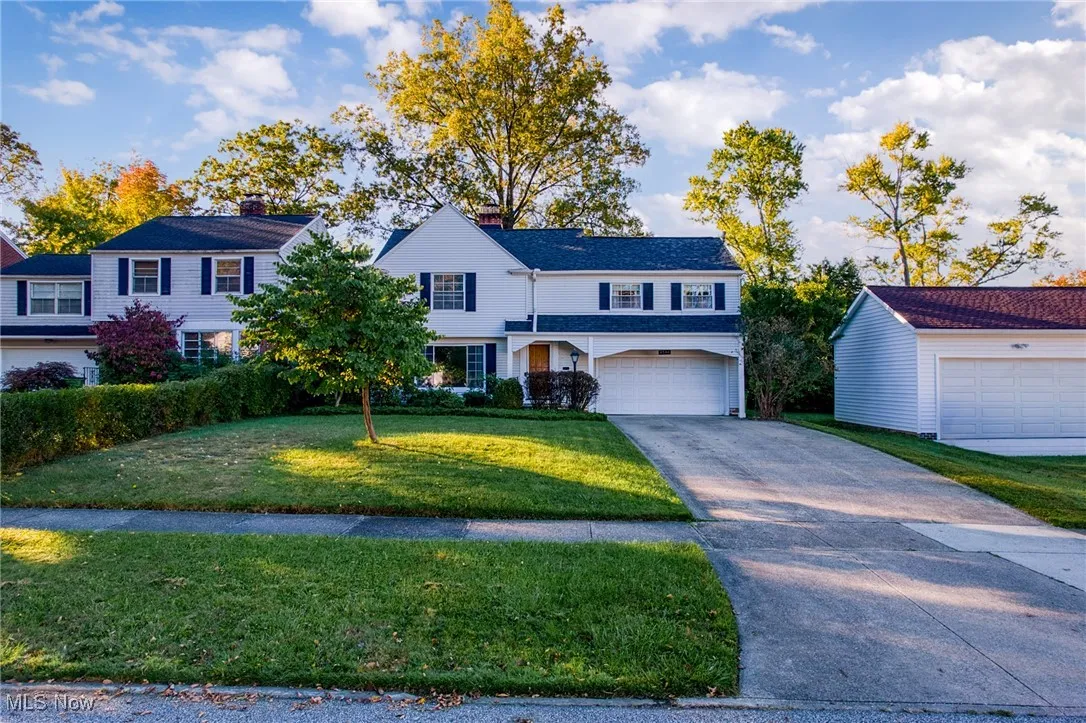 Traditional-style house featuring a front yard, driveway, an attached garage, and a chimney