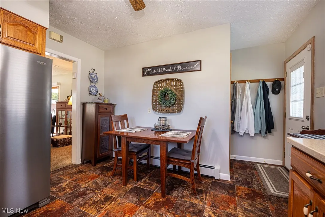Dining space featuring a textured ceiling, dark stone finish floors, and a baseboard heating unit