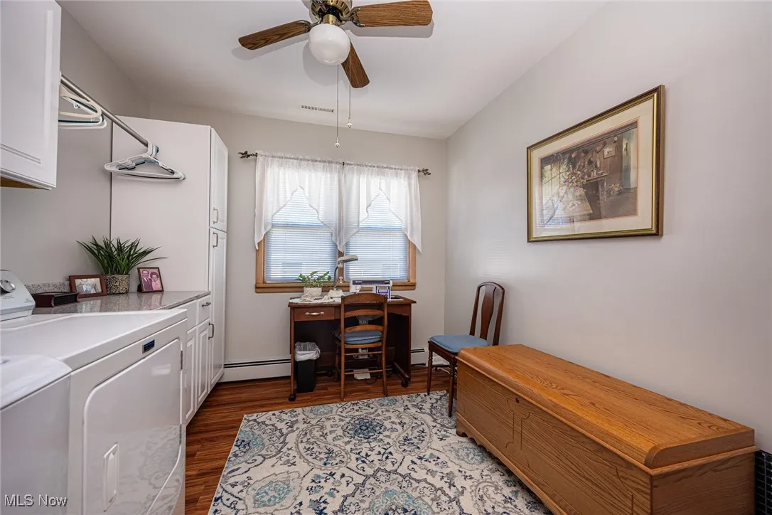 Office area with dark wood-type flooring, a baseboard radiator, ceiling fan, and washing machine and dryer