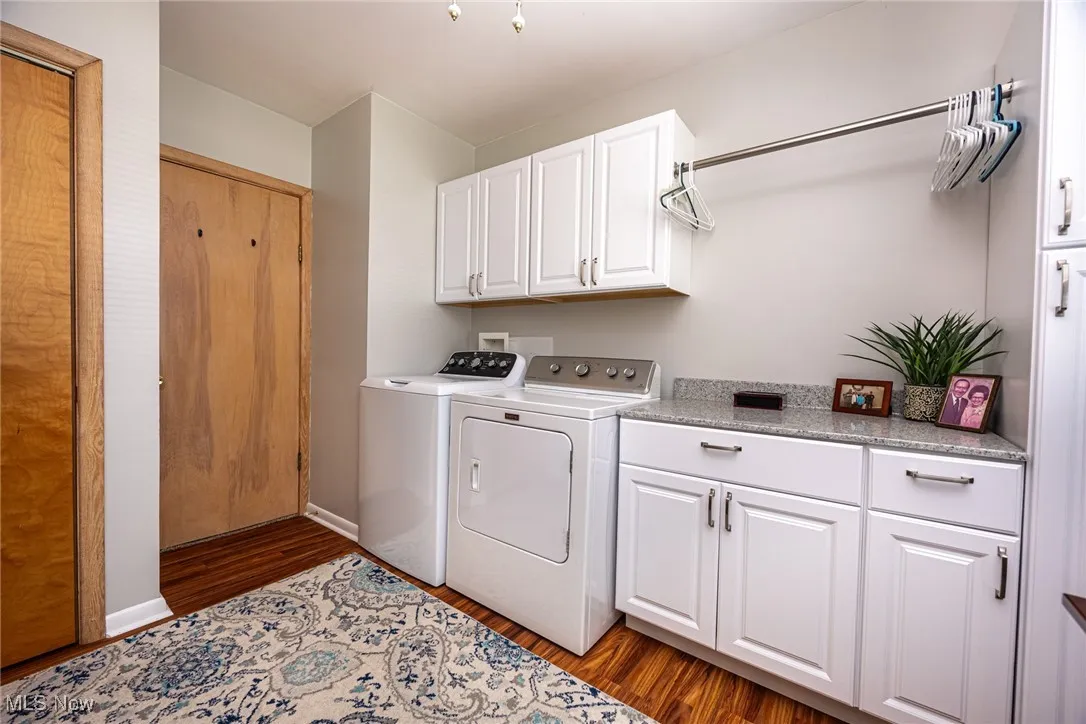 Laundry room featuring dark wood finished floors, cabinet space, and washing machine and dryer