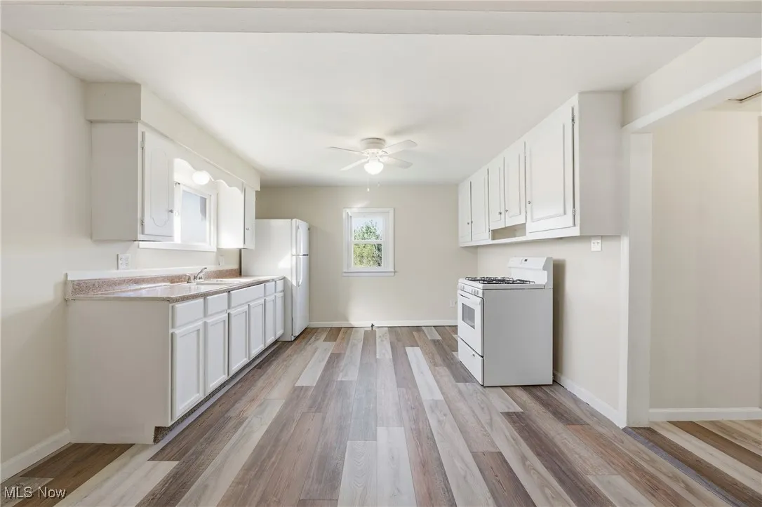 Kitchen with white cabinetry, white appliances, light countertops, and light wood finished​​‌​​​​‌​​‌‌​‌‌​​​‌‌​‌​‌​‌​​​‌​​ floors