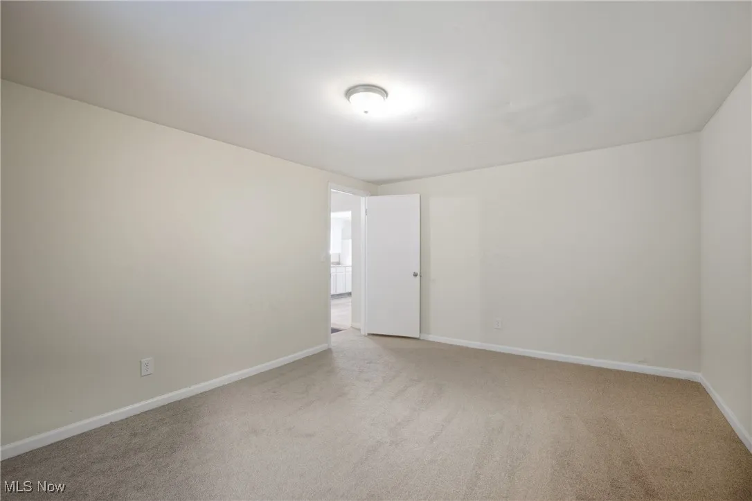 Empty room with light colored carpet and baseboards