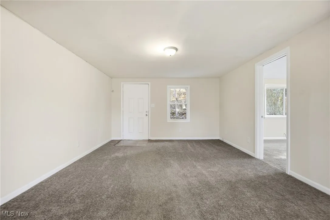 Empty room featuring carpet and baseboards
