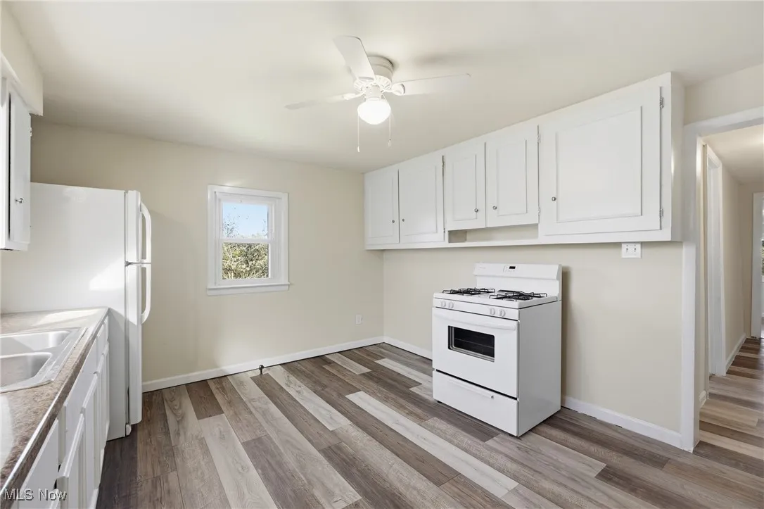 Kitchen featuring white cabinets, white appliances, and light wood-style floors