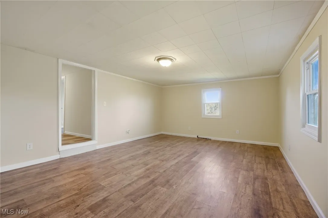 Empty room featuring wood finished floors and crown molding