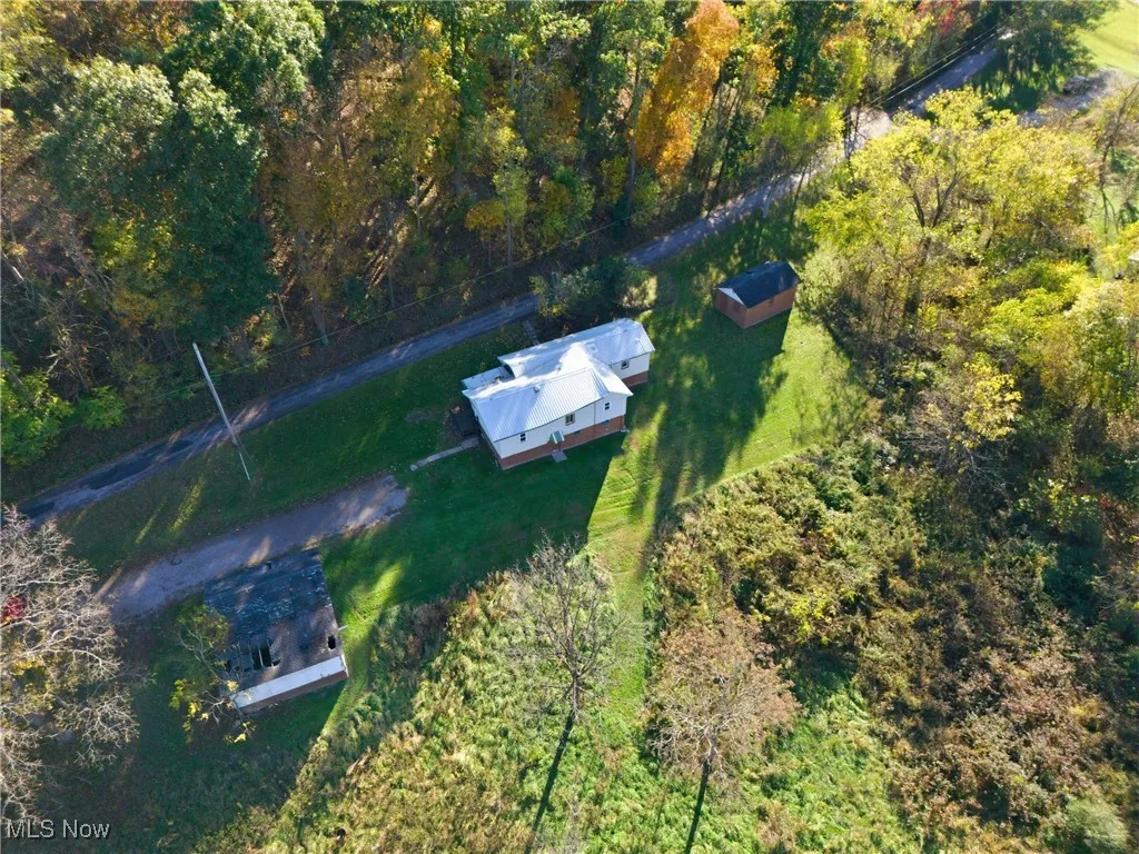 Aerial view of property and surrounding area with a forest