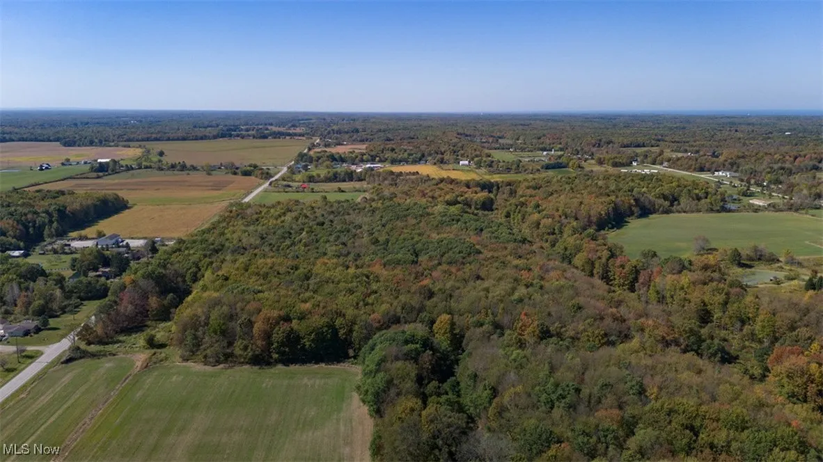 Aerial view of property and surrounding area featuring a forest and rural landscape