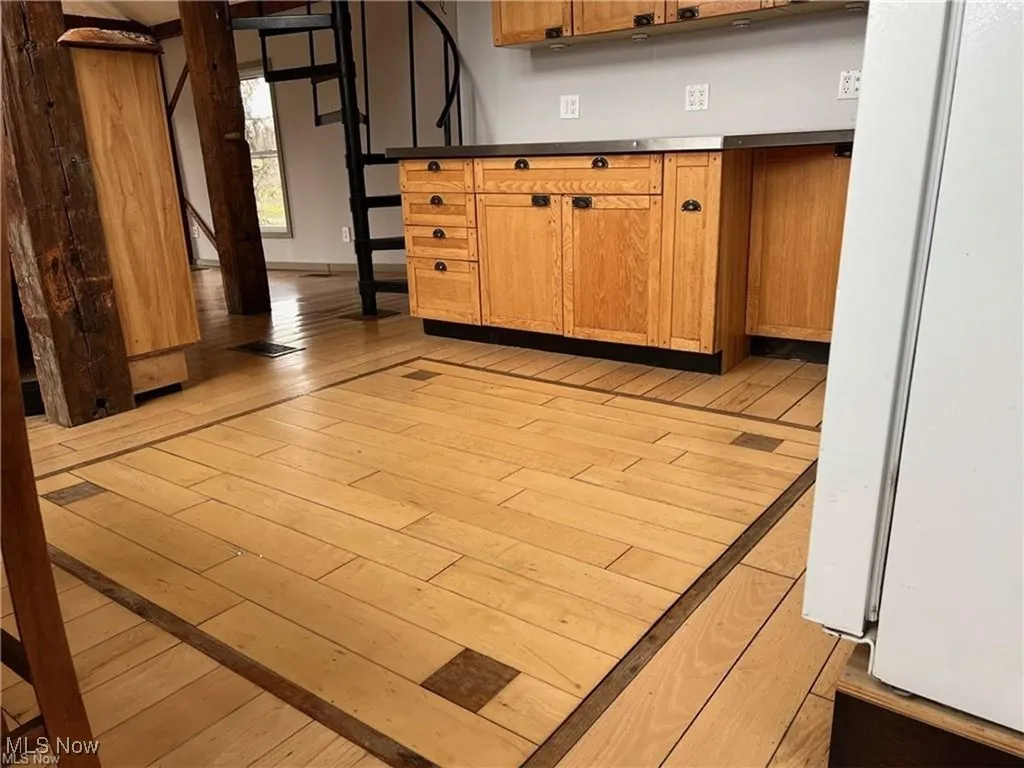 Kitchen with light wood-style floors, freestanding refrigerator, and brown cabinetry