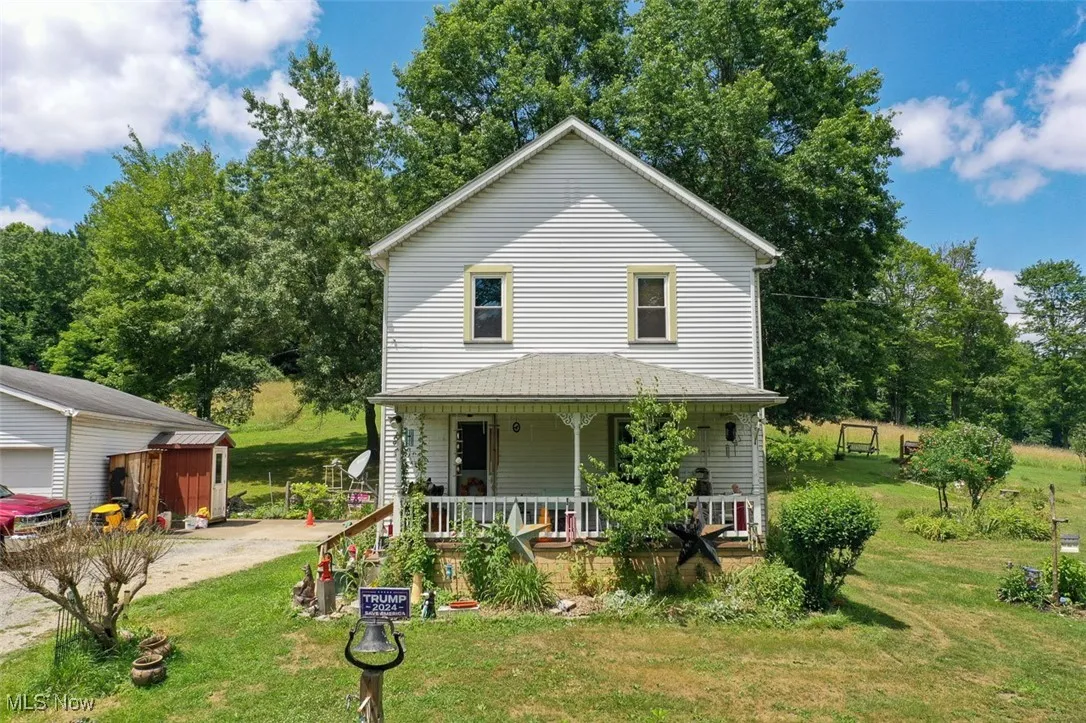 View of front of property with a porch, a front lawn, and an outdoor structure