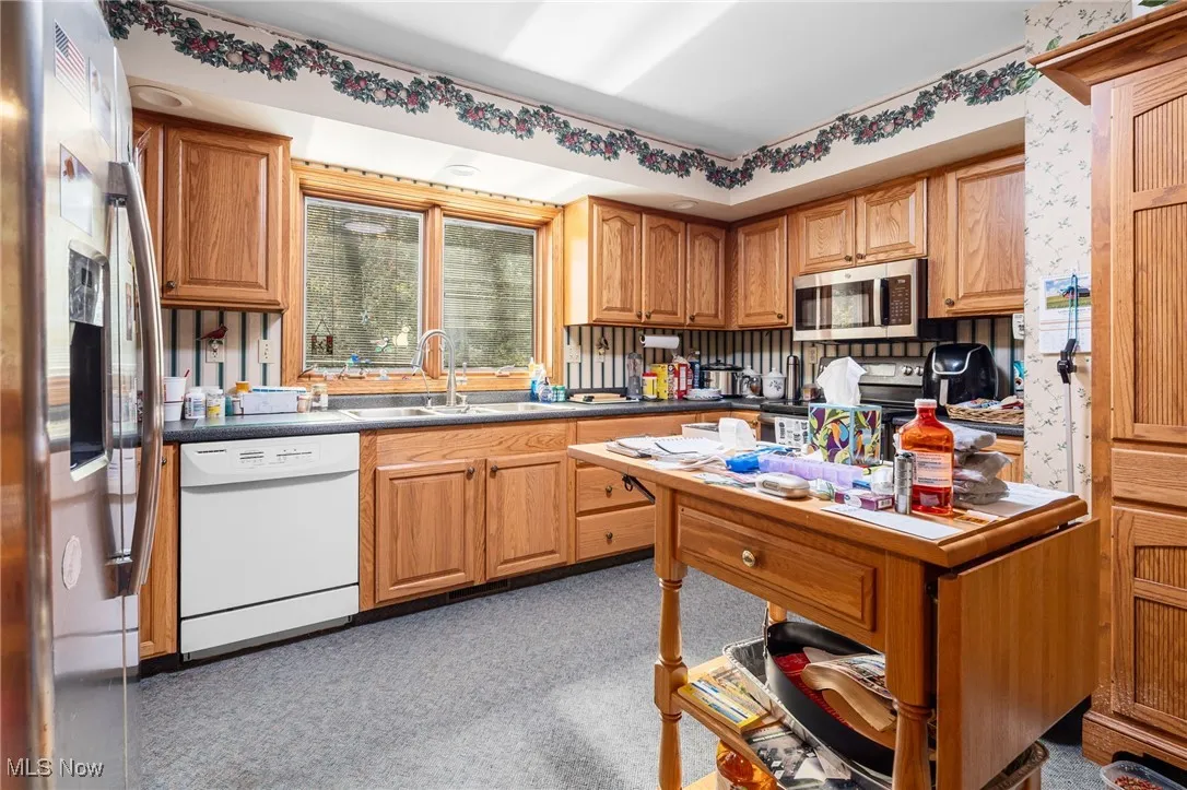 Kitchen featuring appliances with stainless steel finishes, dark countertops, and brown cabinets