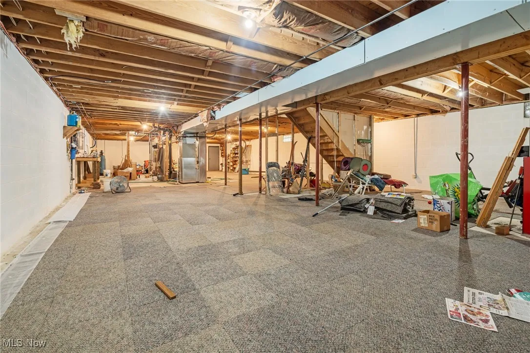 Unfinished basement with stairs and heating unit