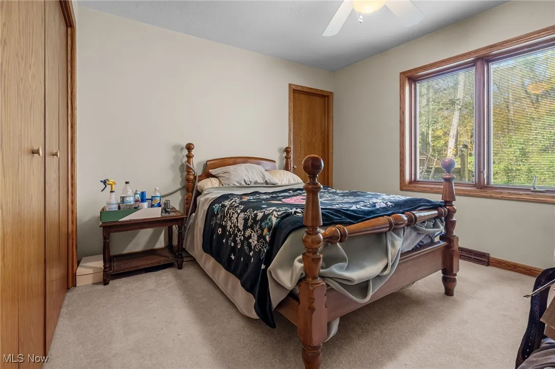 Bedroom with light carpet, a ceiling fan, and a closet