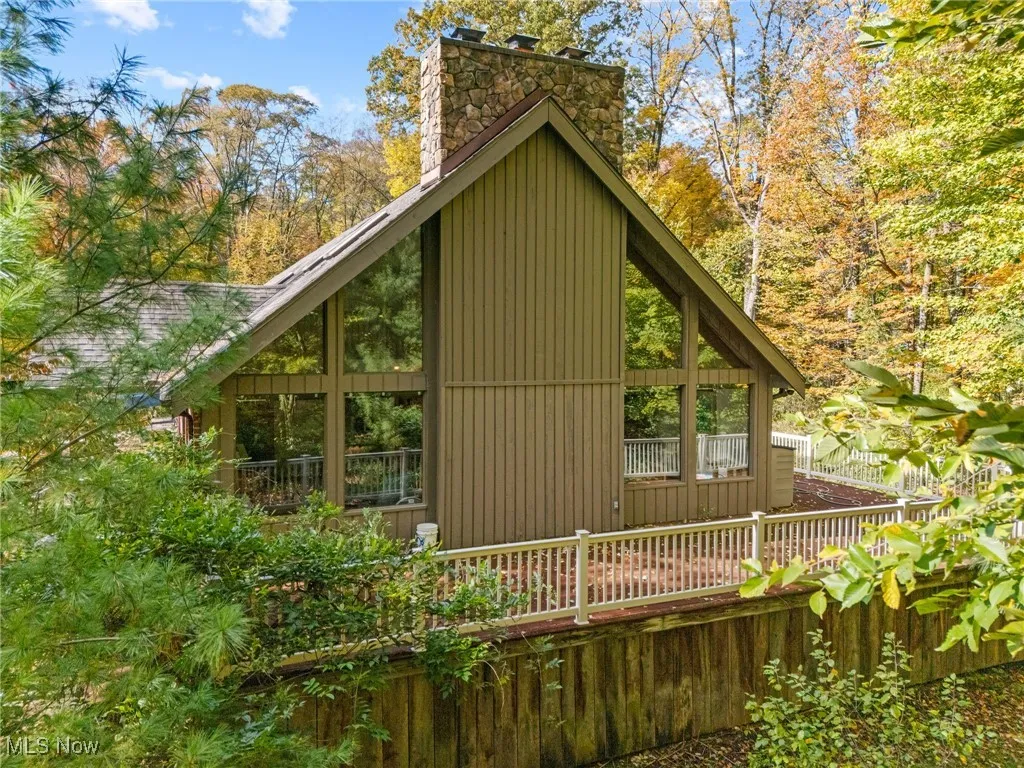 View of home's exterior featuring a chimney and a wooded view
