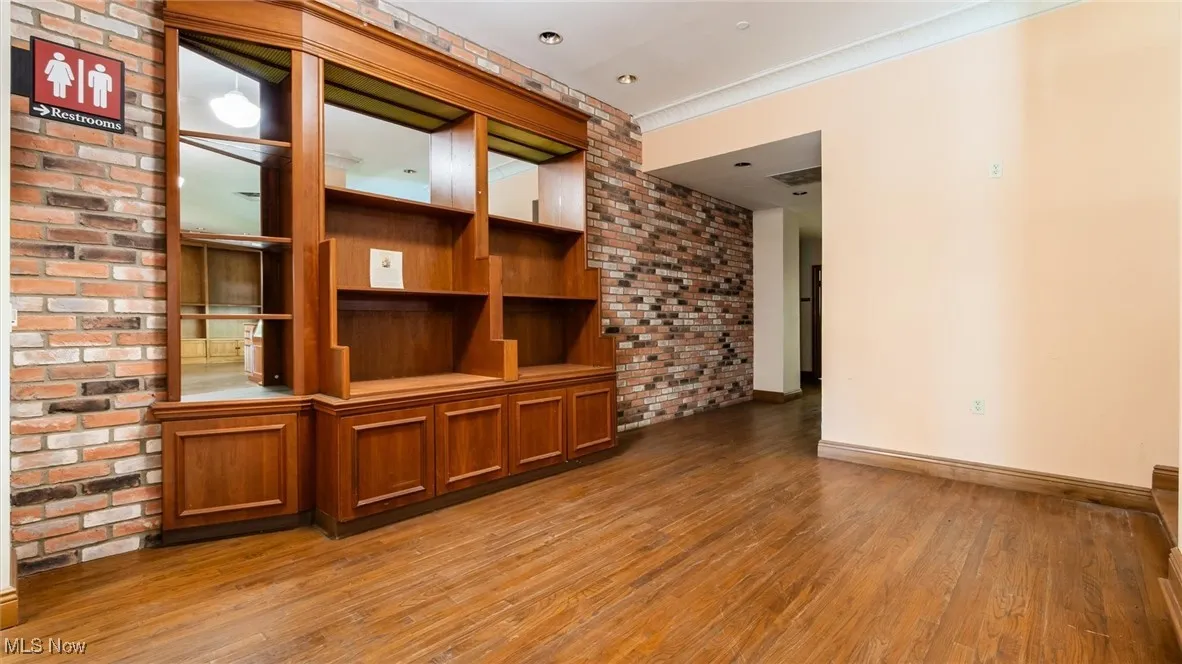 Empty room featuring dark wood finished floors and brick wall