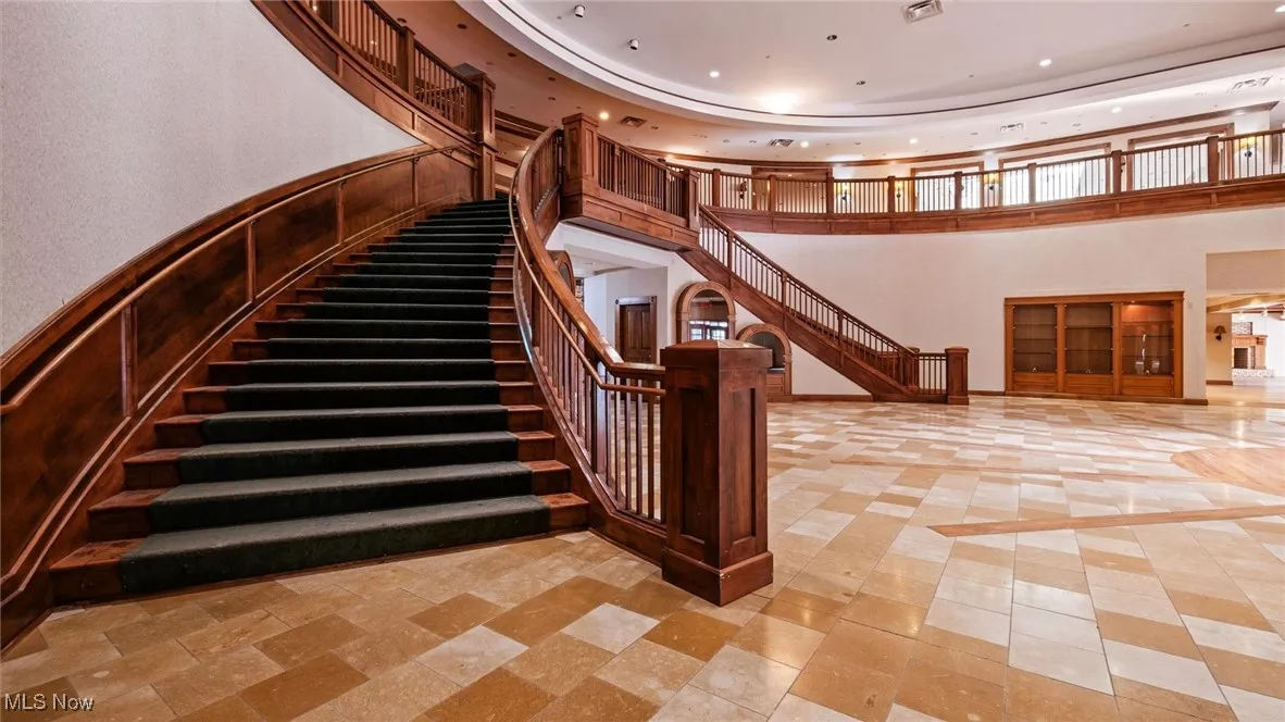 Staircase with a high ceiling, recessed lighting, and a tray ceiling