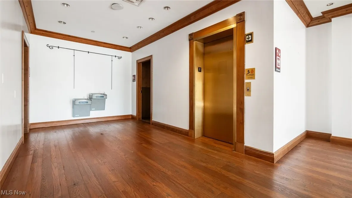 Hallway with crown molding, hardwood / wood-style floors, and elevator