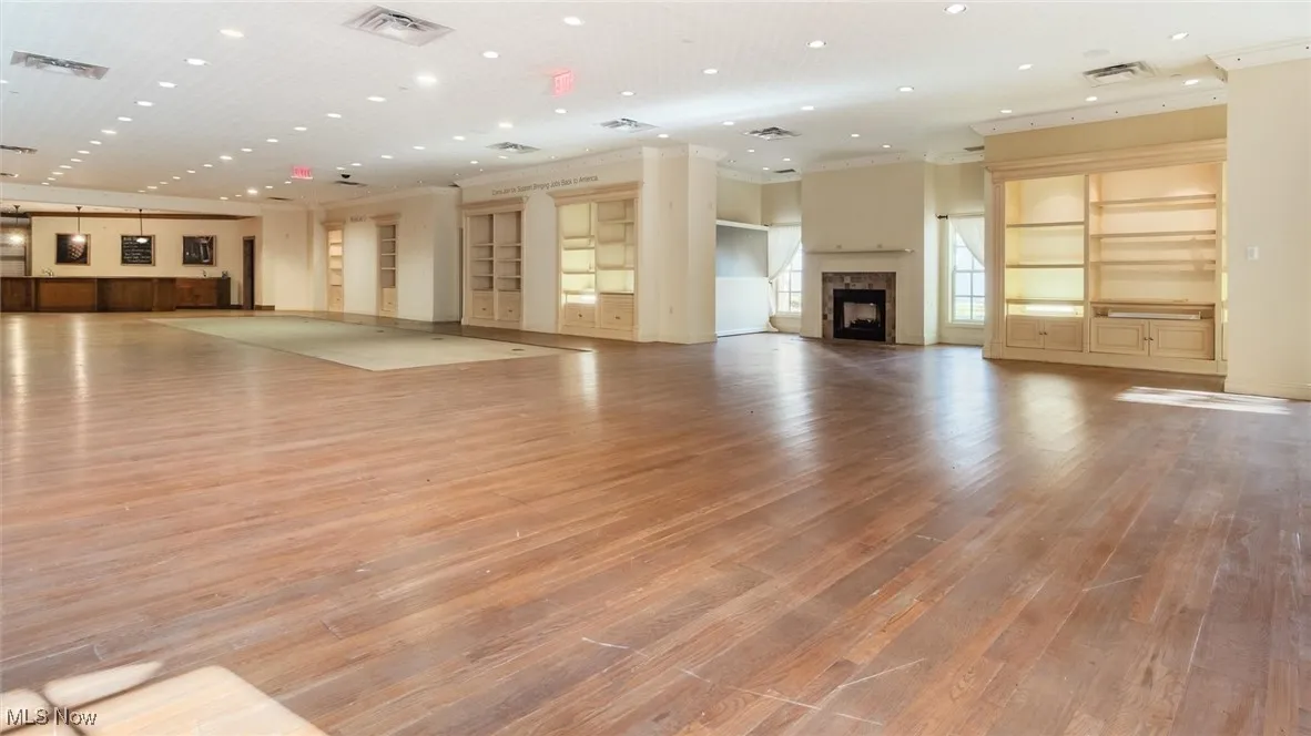 Unfurnished living room with a fireplace, light wood finished floors, crown molding, and recessed lighting