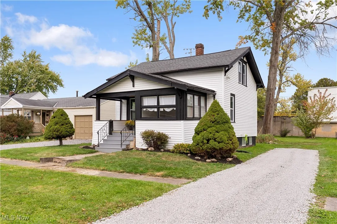 View of front of home with a chimney, a front yard, a shingled roof, and driveway