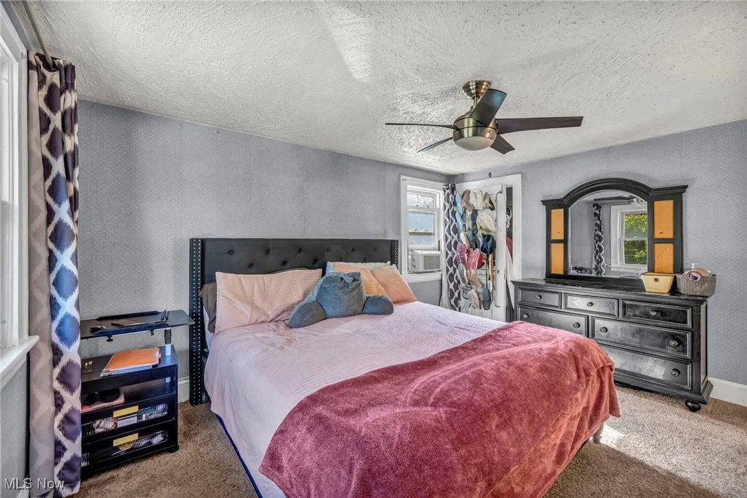 Carpeted bedroom with multiple windows, a textured ceiling, and a ceiling fan