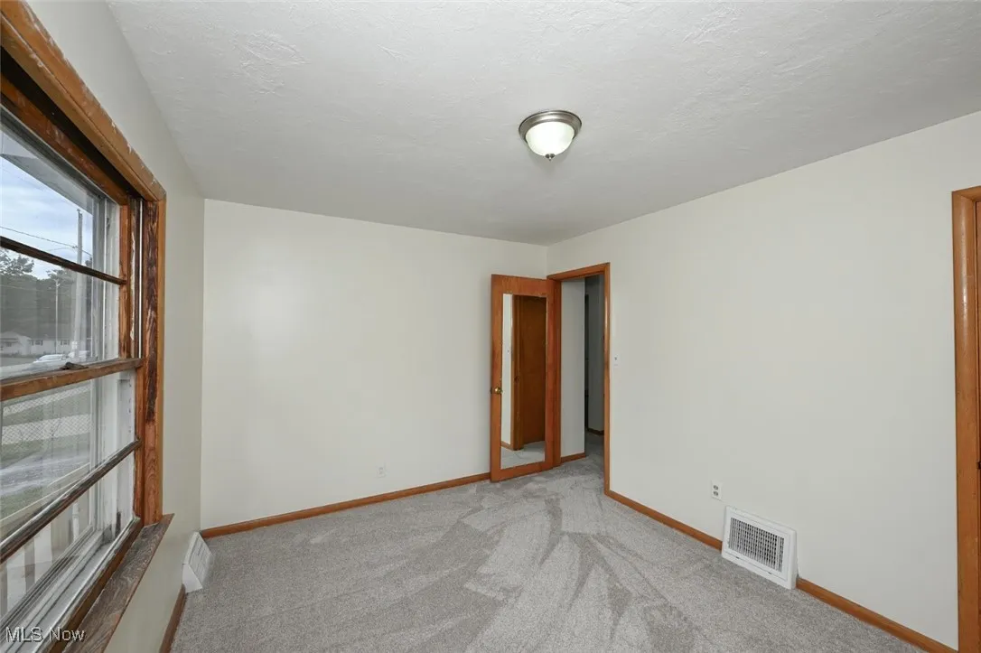 Carpeted empty room featuring baseboards and a textured ceiling
