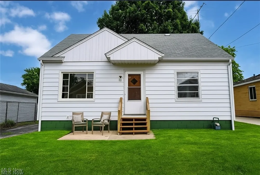 View of front of house with a shingled roof, entry steps, a patio area, and board and batten siding