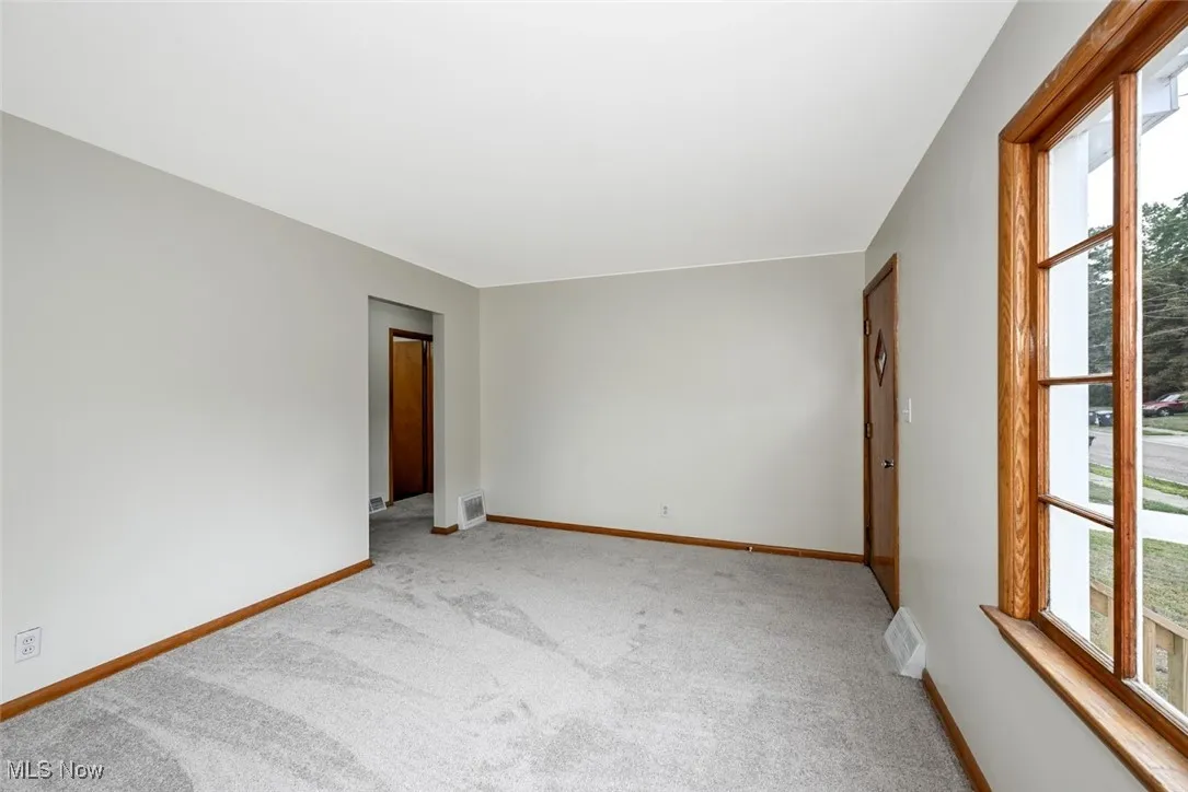 Empty room with light carpet and baseboards