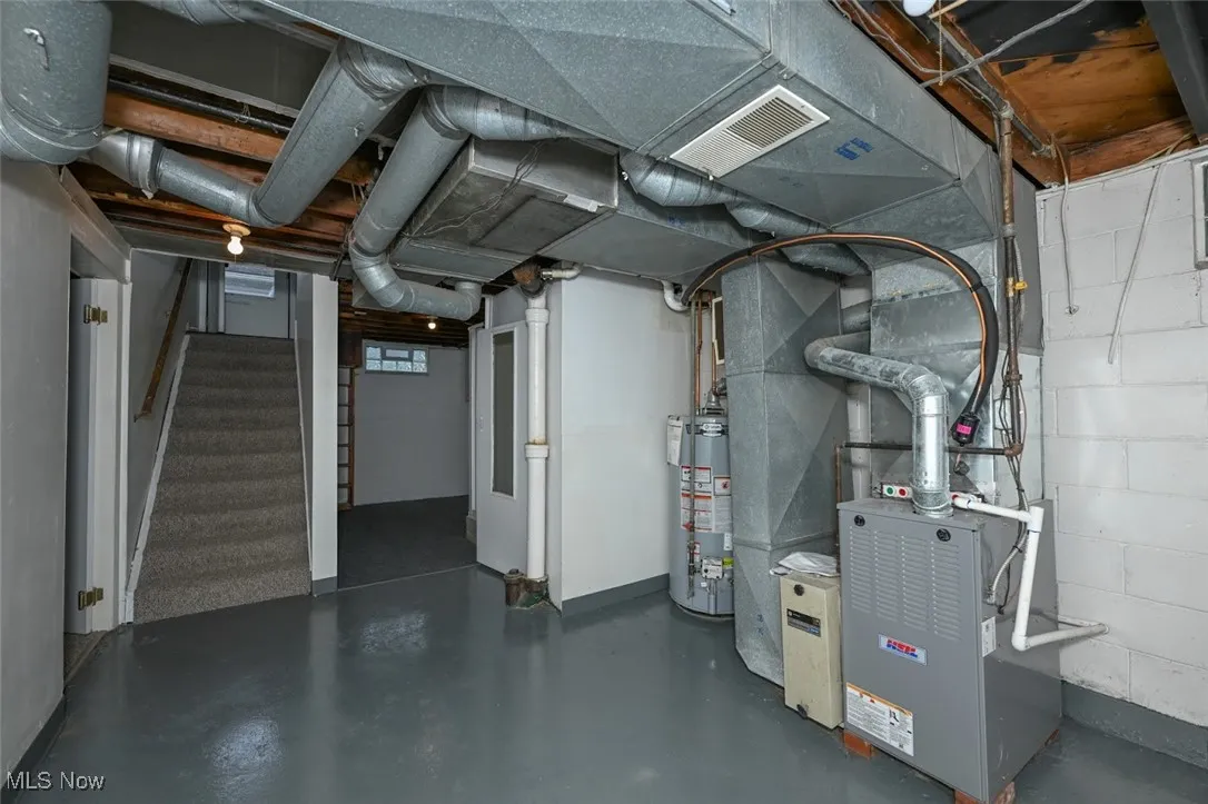 Below grade area featuring heating unit, stairs, and water heater