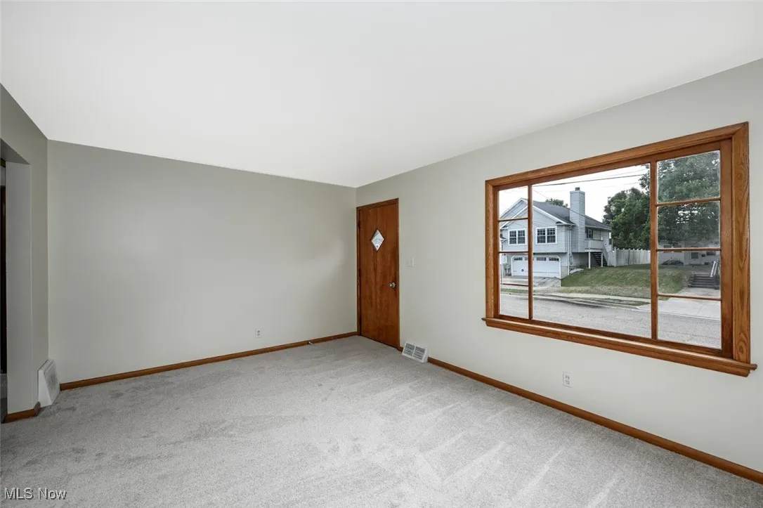 Unfurnished living room featuring carpet floors and baseboards