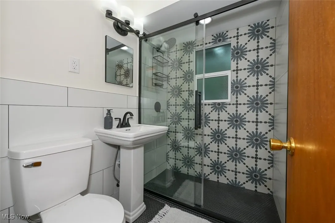 Full bathroom with a shower stall and tile walls