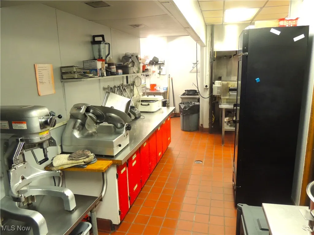 Kitchen featuring freestanding refrigerator, stainless steel countertops, and red cabinetry