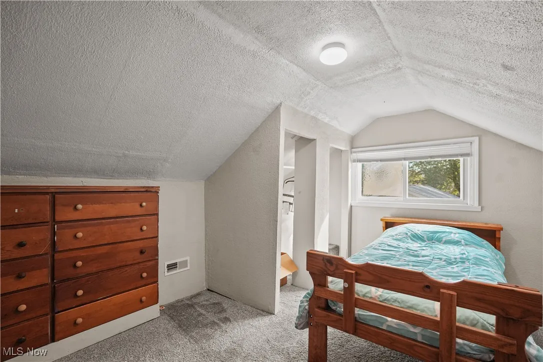Carpeted bedroom with a textured ceiling and lofted ceiling